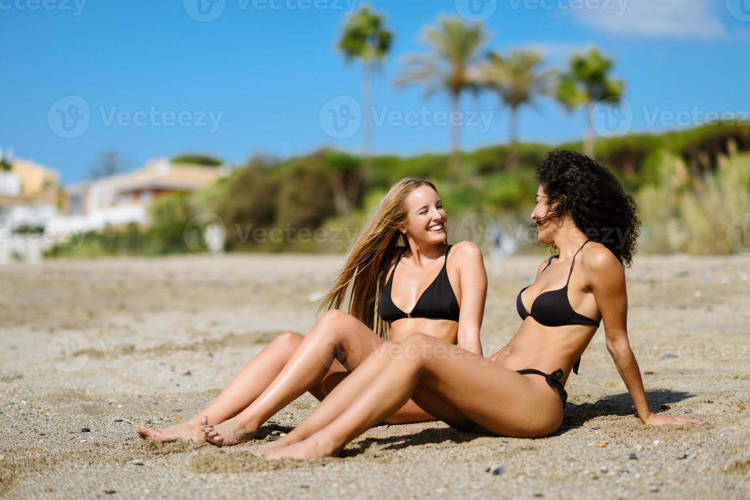 Two young women with beautiful bodies in swimwear on a tropical beach photo