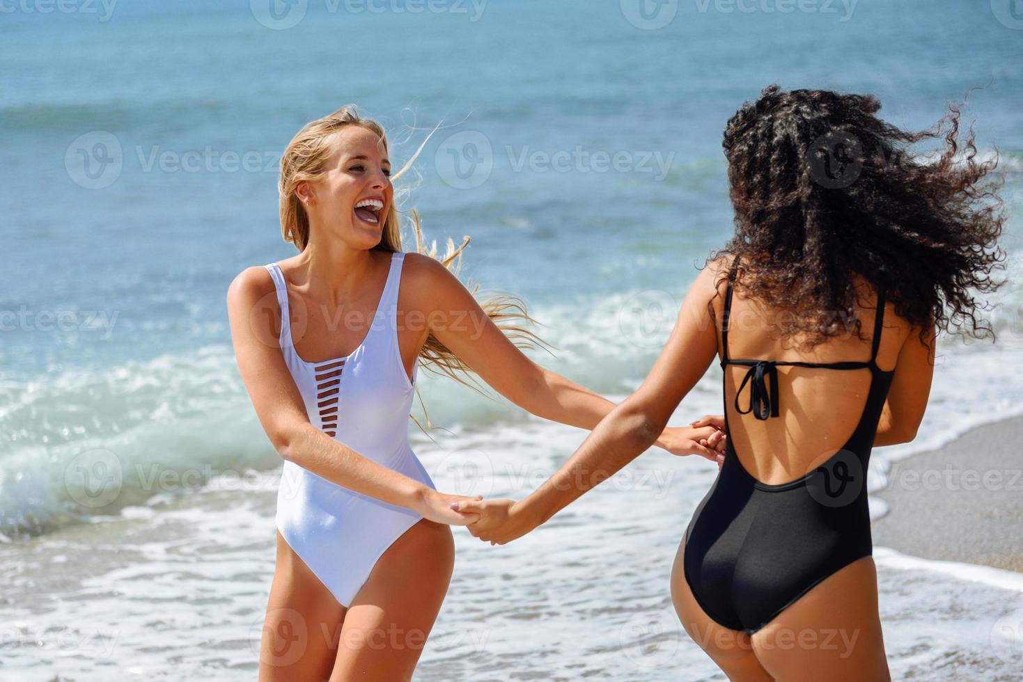 Two women in swimsuit having fun on the beach photo