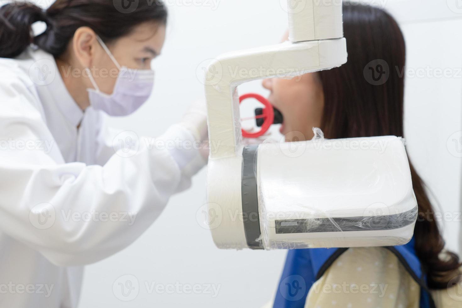 Asistente de dentista con máquina de rayos X para escanear el diente de una joven asiática en la clínica. concepto de odontología y salud foto
