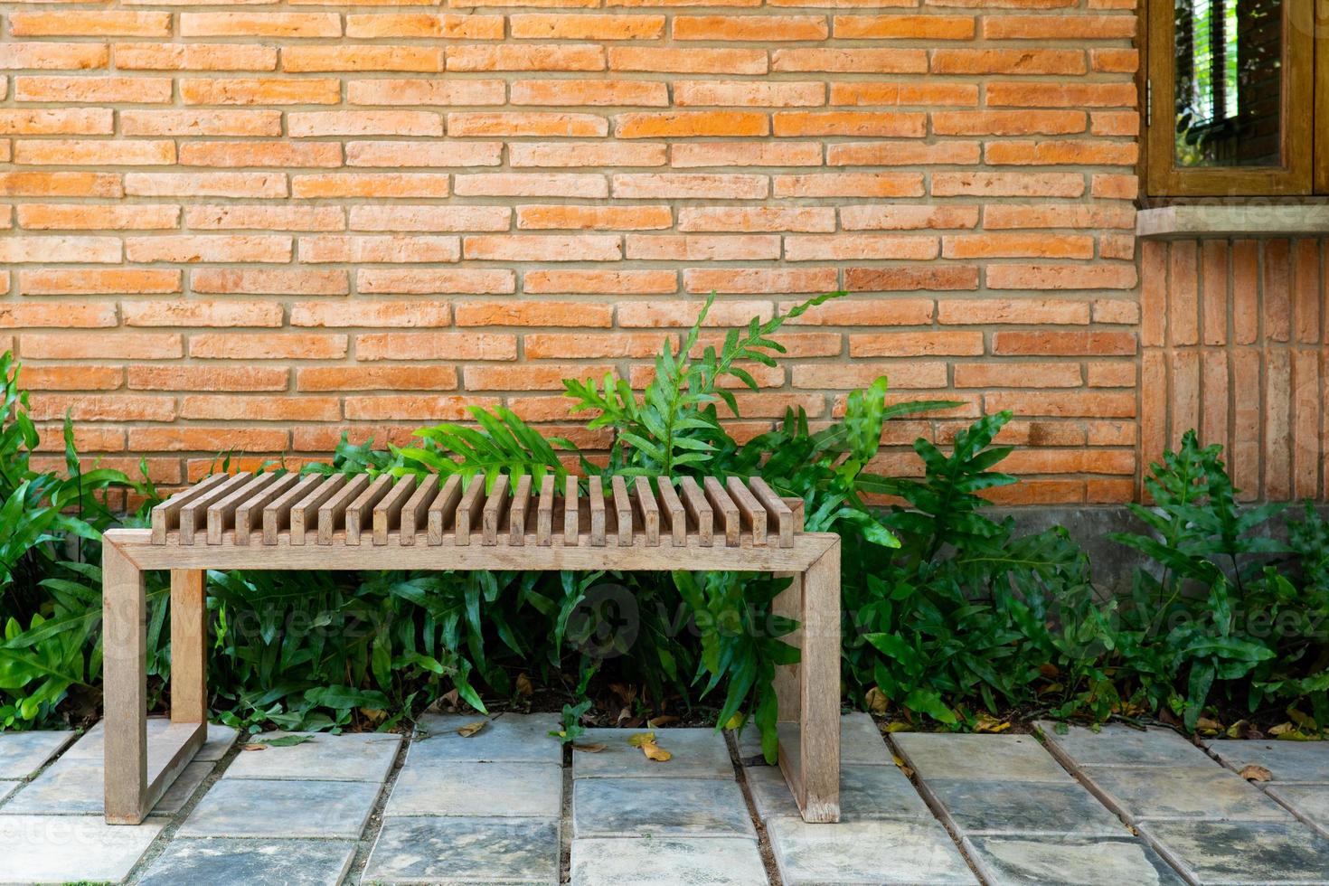 wooden bench outside brick wall building photo