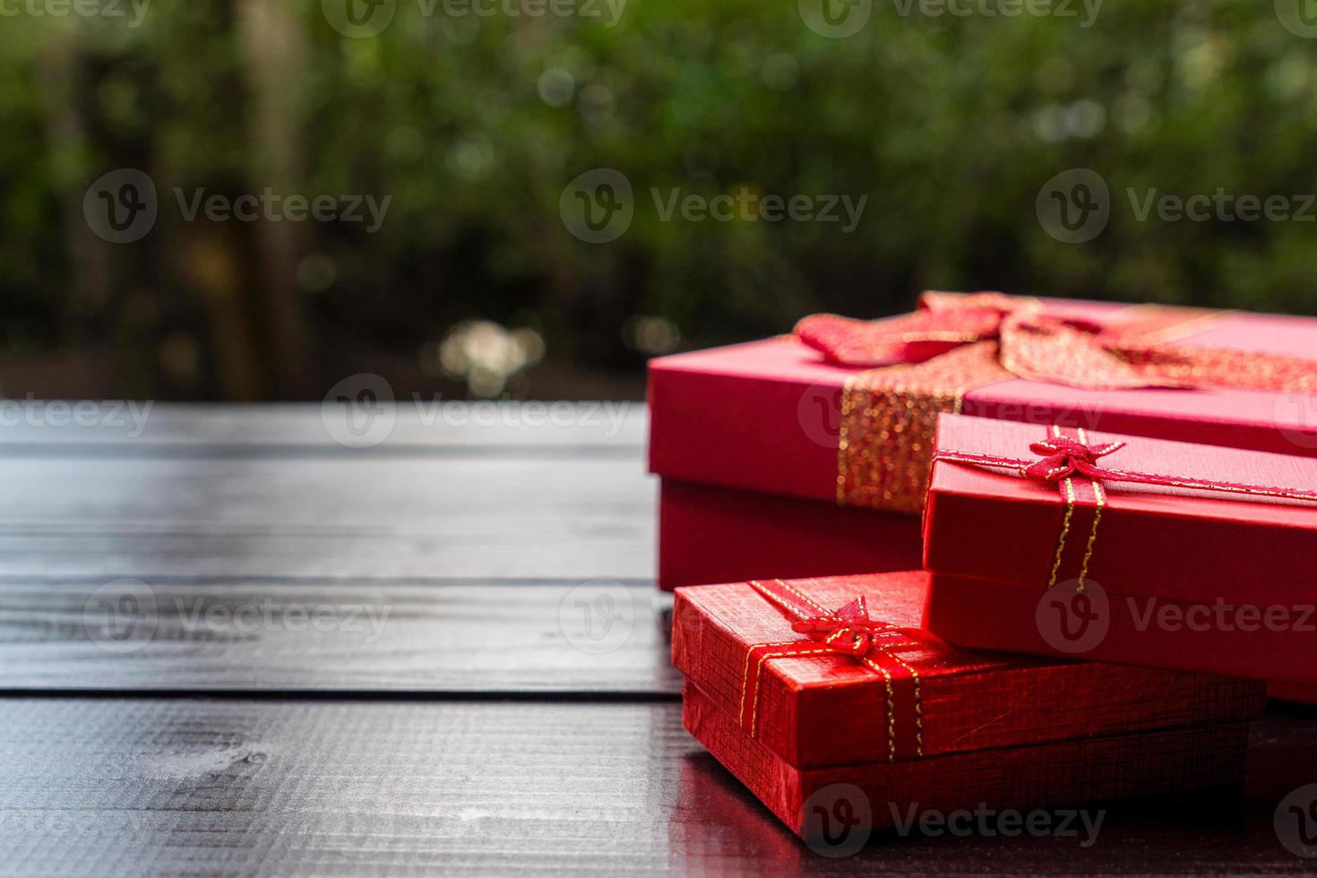 presenta caja roja sobre mesa de madera en el jardín. preparándose para la celebración de navidad y año nuevo foto