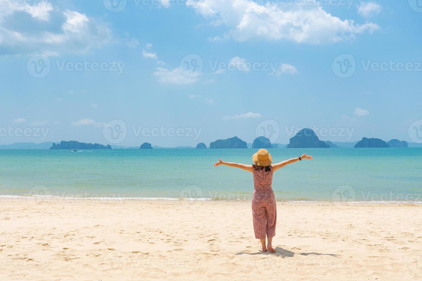 young asian woman standing on the beach and looking at blue sea in sunny day during sumer vacation photo