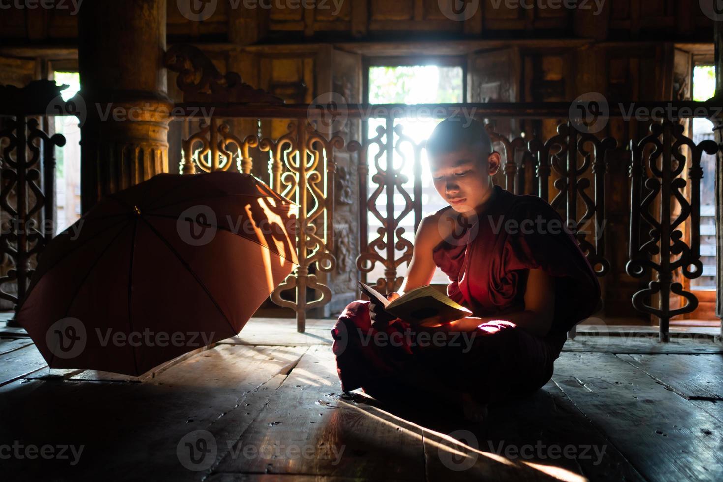 Joven monje novicio asiático leyendo un libro en el monasterio foto