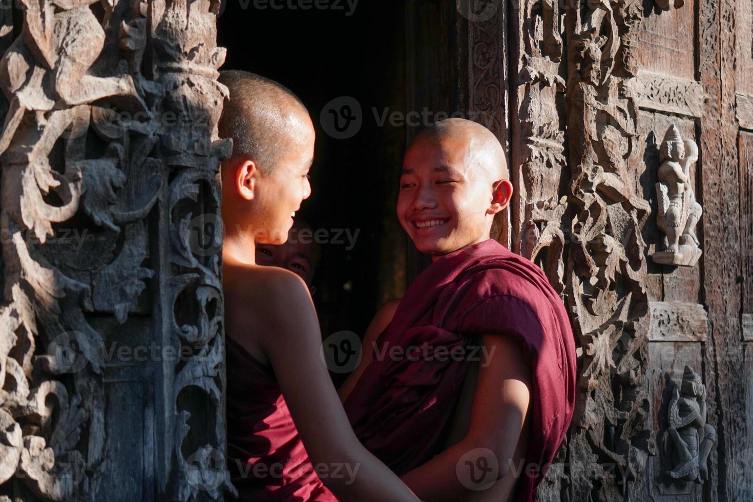 young aian novice monk talking and sitting together at door of monasery photo