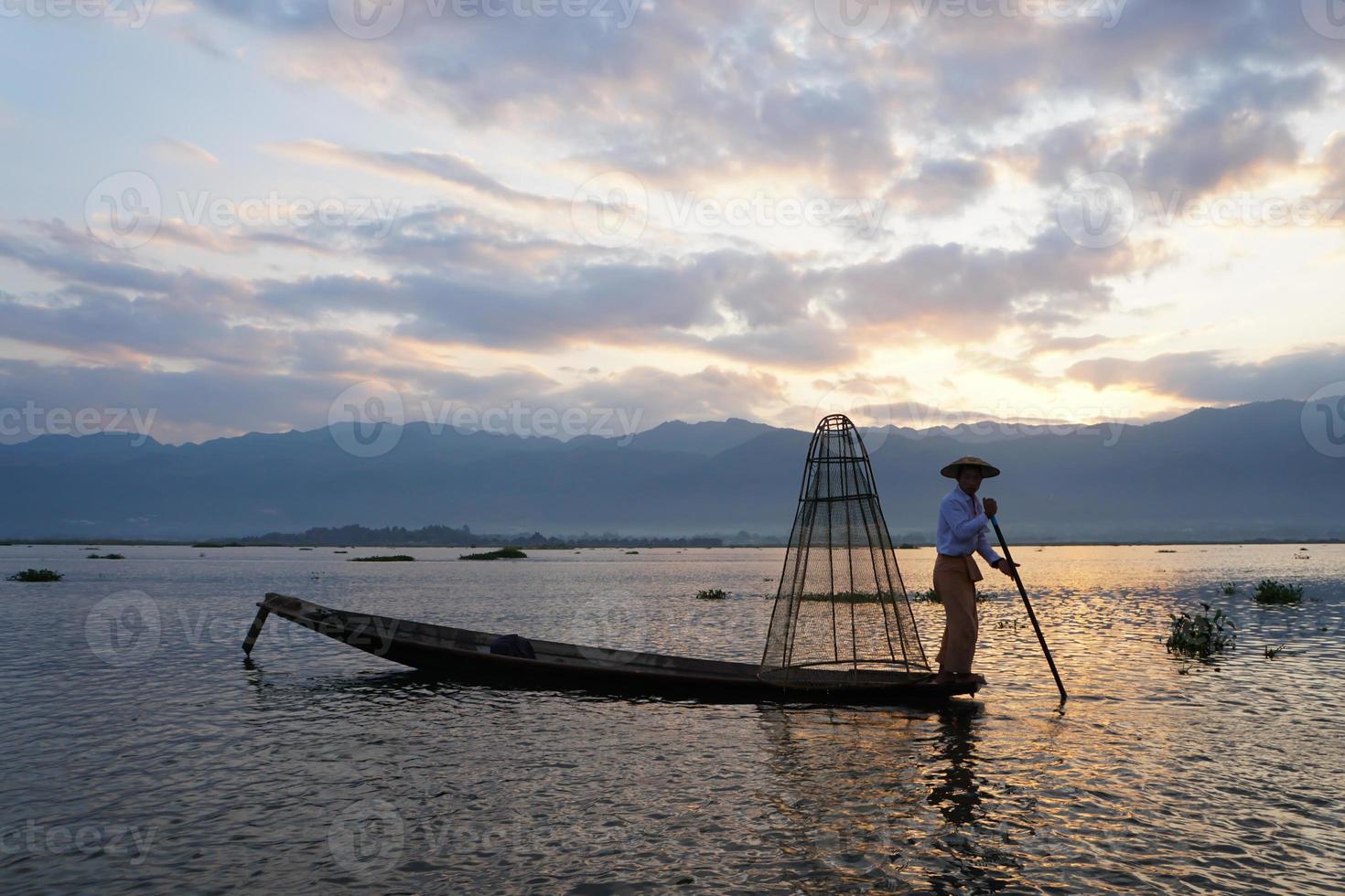 silhouette of local fisherman using coop to catching in inle lake at sunrise photo