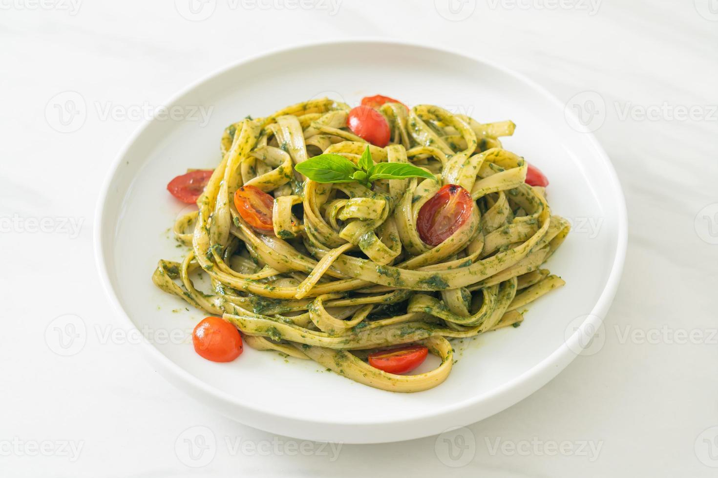 espaguetis fettuccine con salsa pesto y tomates foto