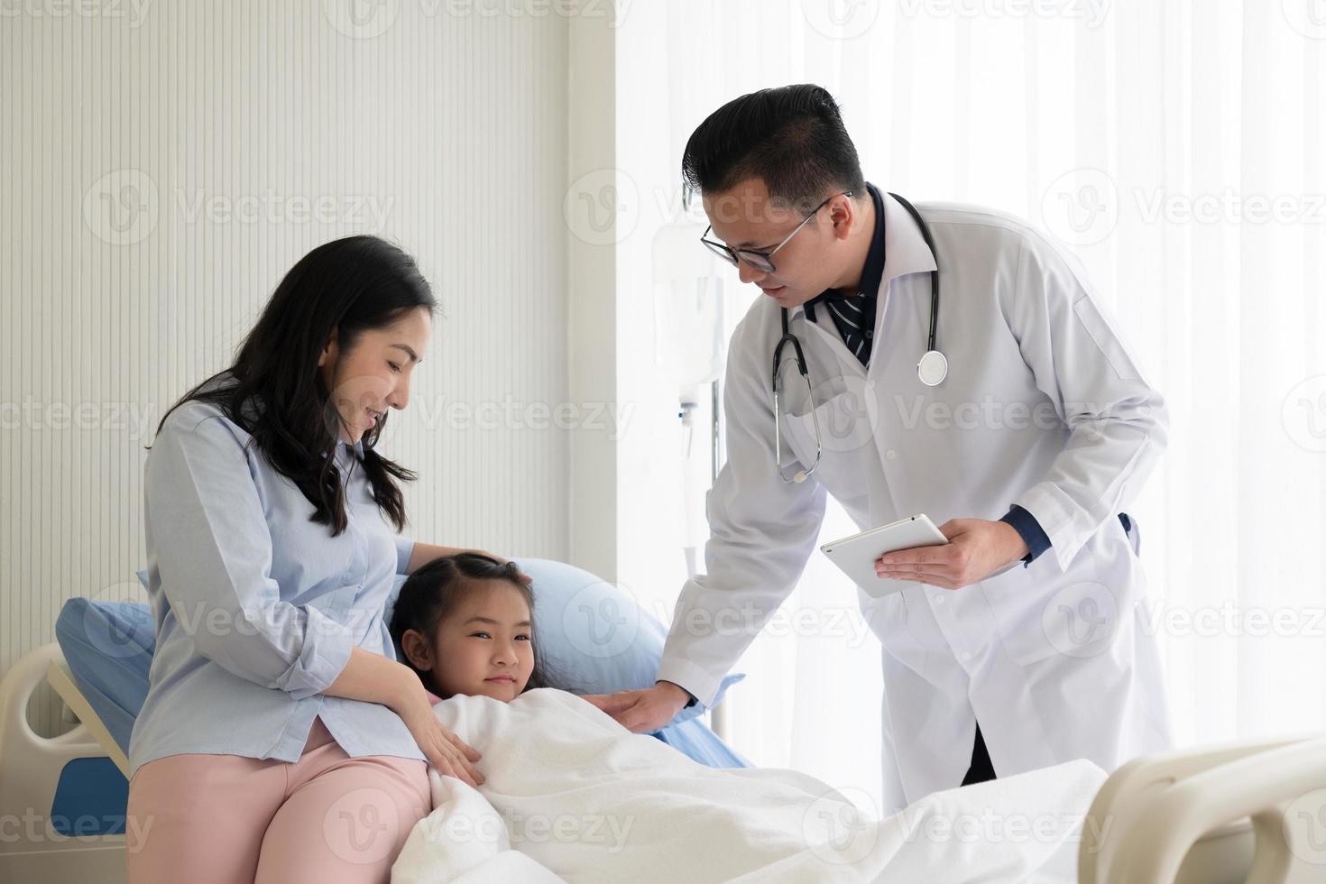 asian doctor visit young girl and mother who is sick and admitted at pediatric ward in hospital. healthcare and medical concept photo