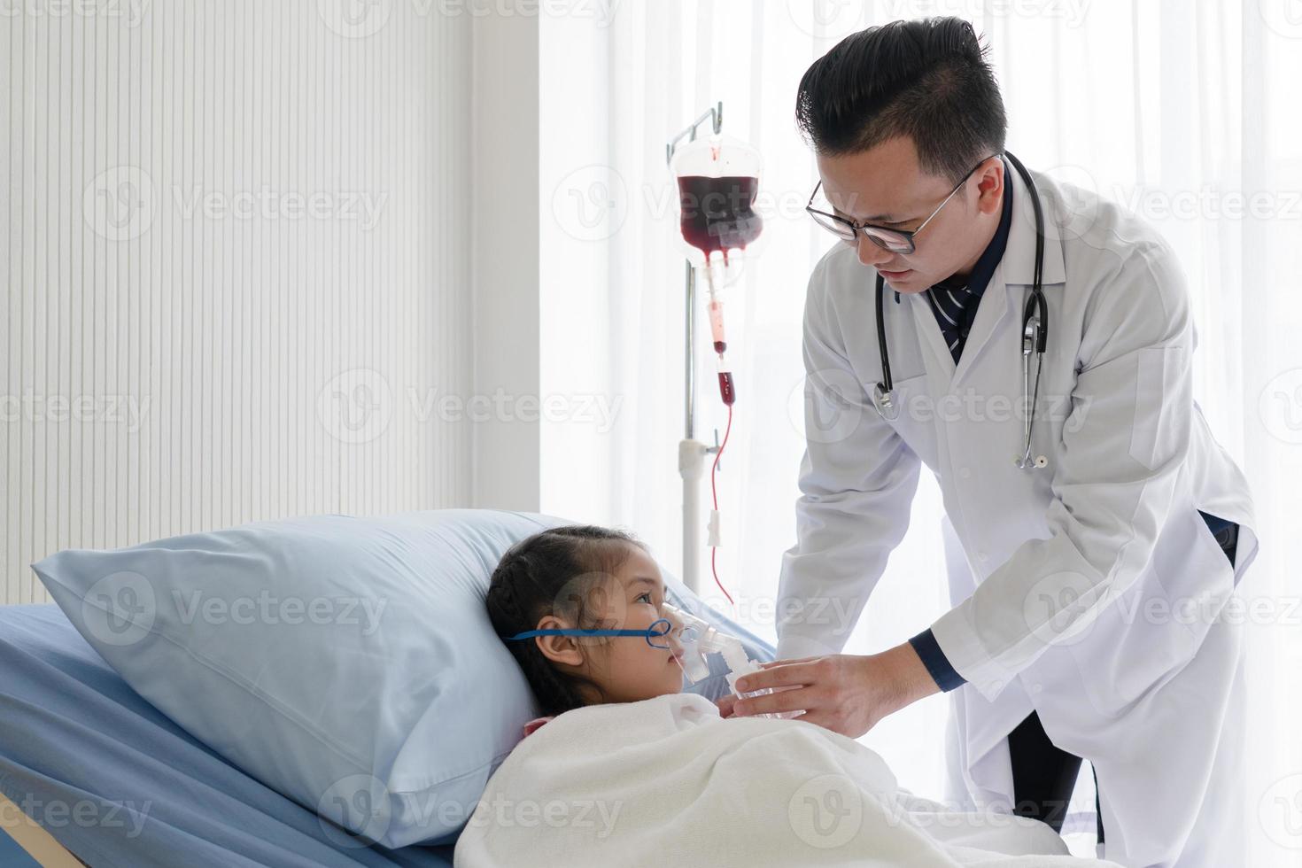 doctor give oxygen therapy to young asian girl who is sick and has pneumonia in hospital pediatric ward. healthcare and medical concept photo