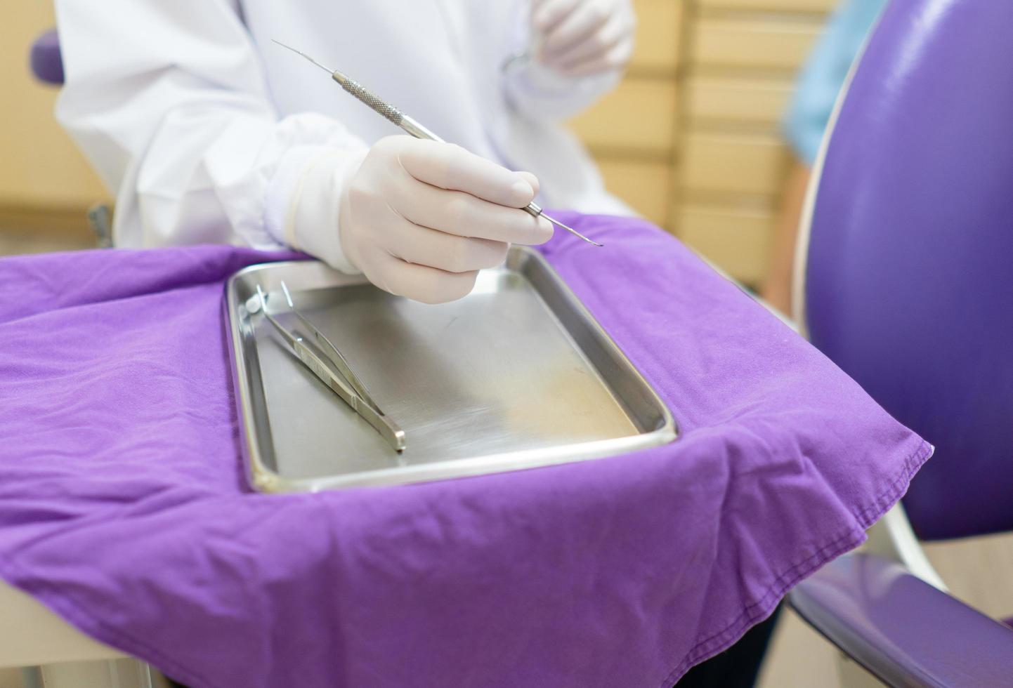 dentista con guantes y sosteniendo una herramienta dental para limpiar el diente del paciente en la clínica. concepto de salud y odontología foto