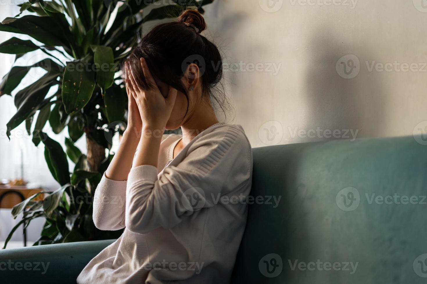 Stressed woman sitting on sofa at home photo