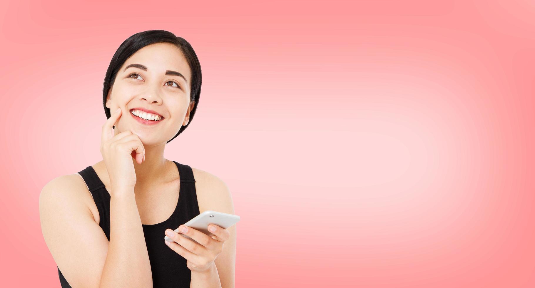 happy korean,chinese woman isolated on pink background. Girl holding phone,copy space photo