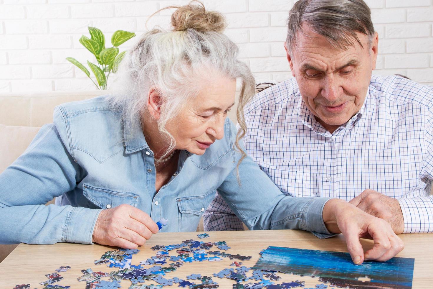 Senior couple solving jigsaw puzzle together at home photo