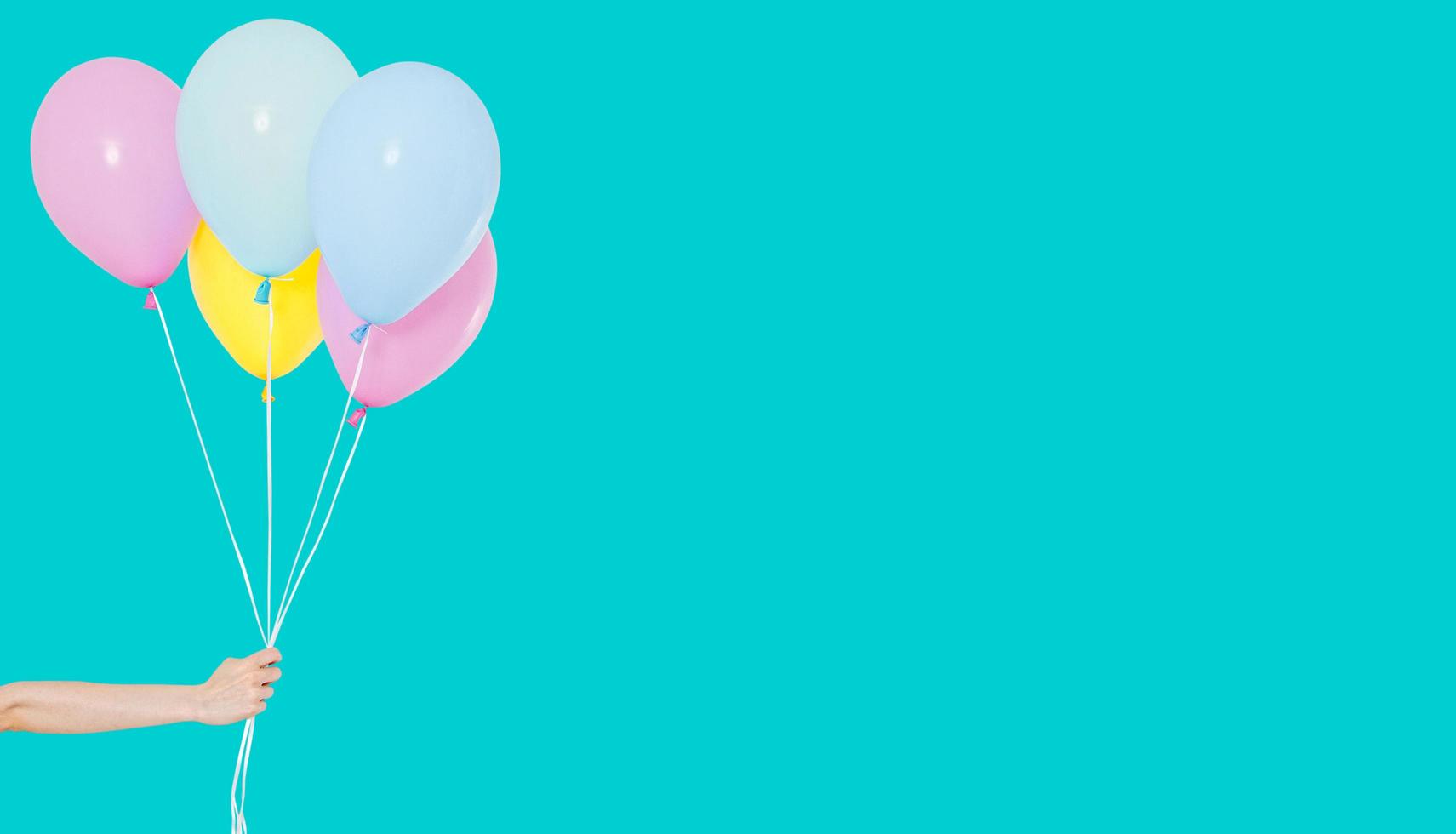 Hand hold colorful balloons on background - copy space photo