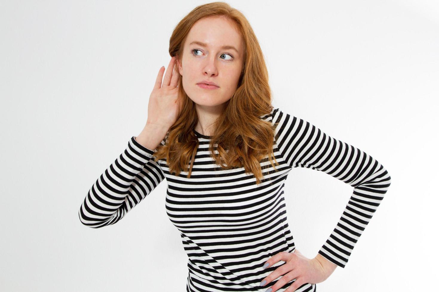 young red head woman listening gossip copy space, Young beautiful red hair lady cupping hand behind ear on white background photo