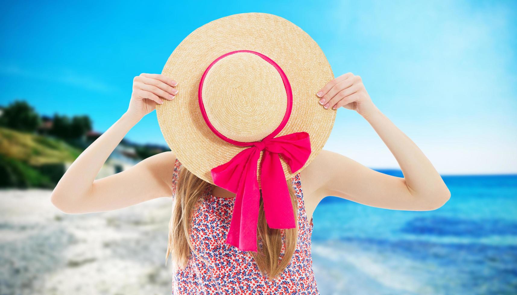 Pretty slim tan blonde stylish woman in straw hat and sunglasses, posing on the paradise tropical beach. Have bright mace up and wearing coloured shirt. photo