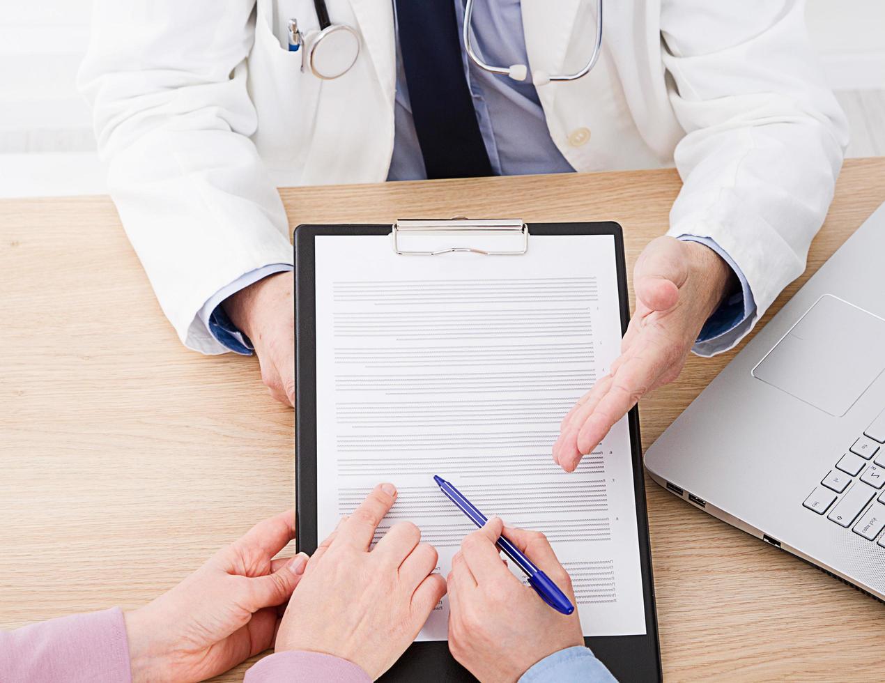 Doctor and patient are discussing something, just hands at the table, medical insurance. photo