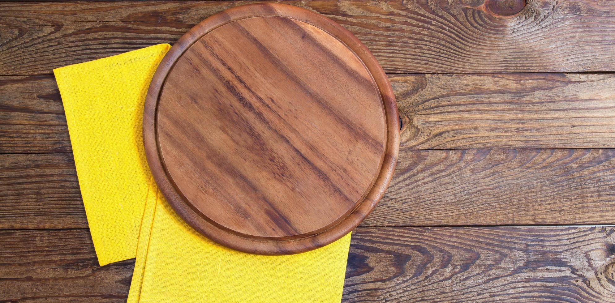 servilleta y tabla para pizza en primer plano de escritorio de madera, mantel. lienzo, paños de cocina en la vista superior de fondo de mesa de madera blanca simulacro. enfoque selectivo foto