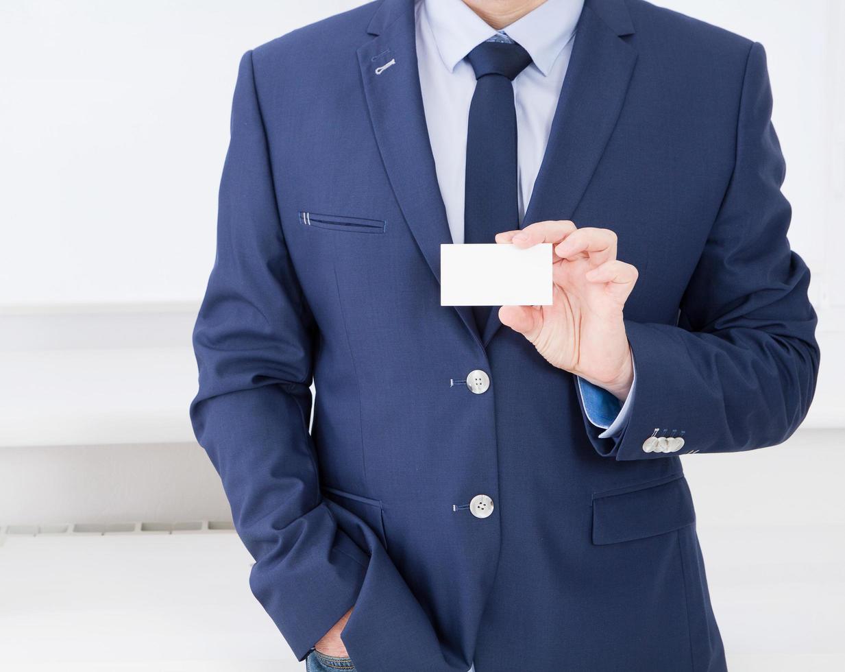 Man's hand showing business card - closeup shot in office, blank, top view photo