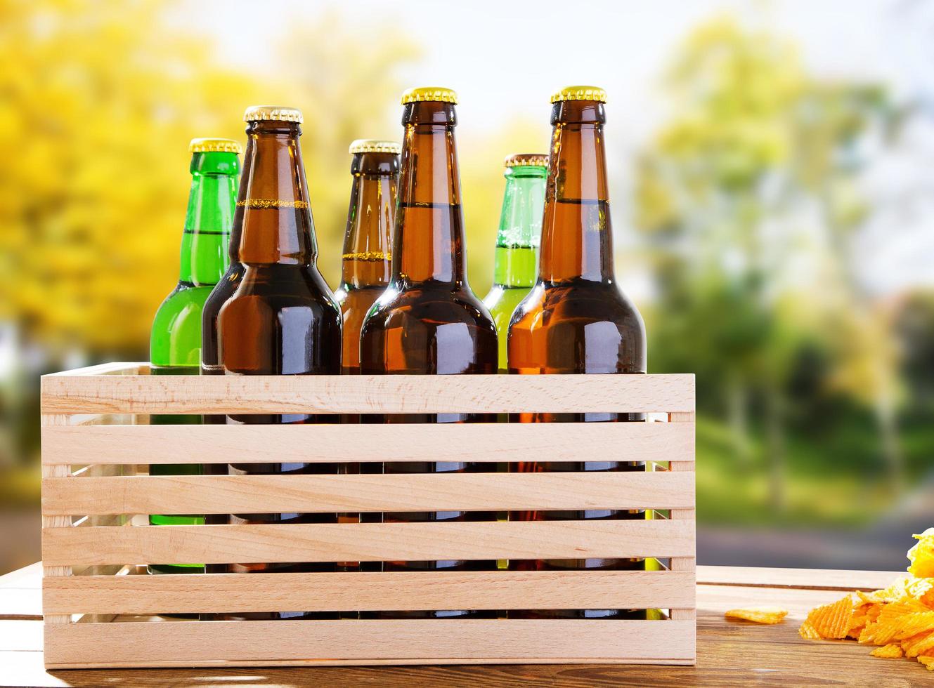 Botellas de cerveza artesanal en la caja de la mesa de madera en el fondo del parque borrosa foto