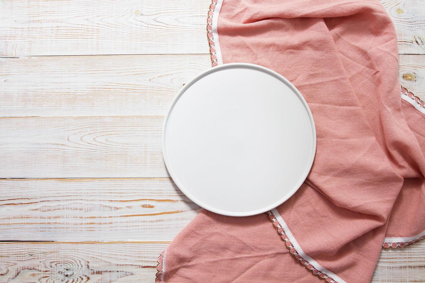 the white plate on pink tablecloth on wooden table top view photo