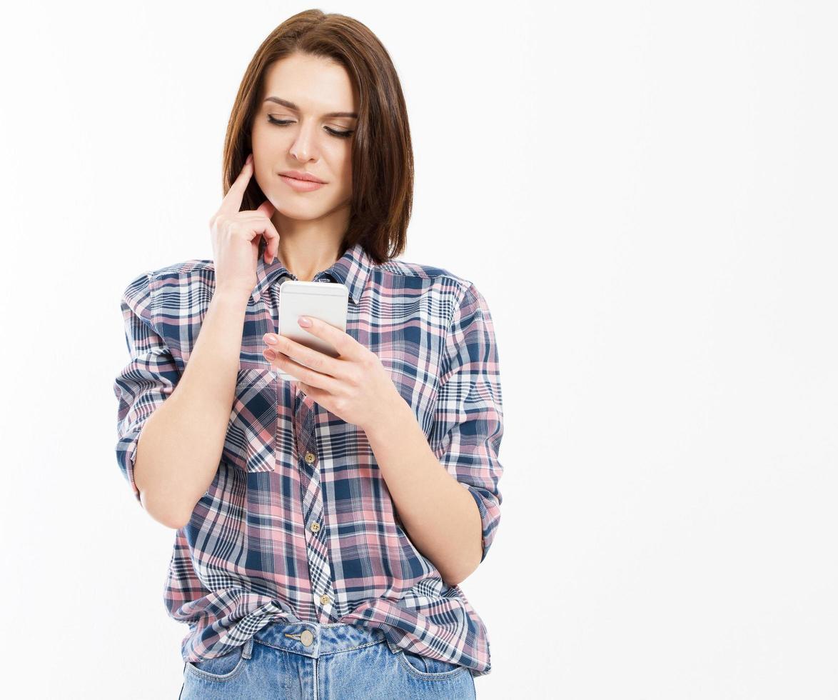 Belleza mujer morena usando y leyendo un teléfono inteligente aislado sobre un fondo blanco, sonriente mujer adolescente sosteniendo smartphone foto