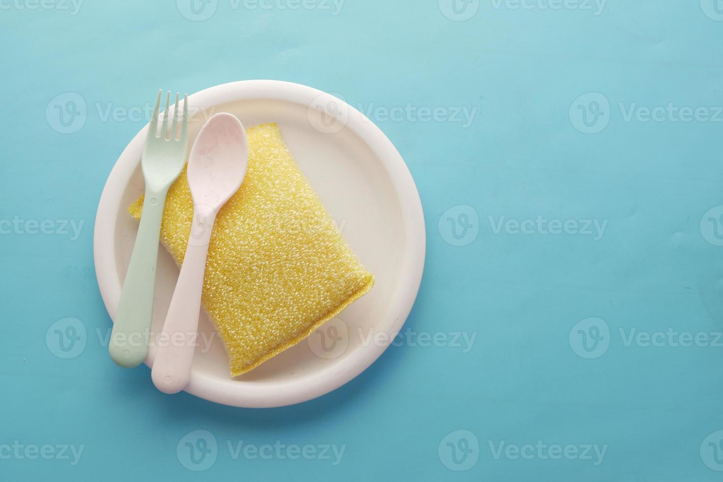 sponge , rubber gloves and colorful plate on blue photo