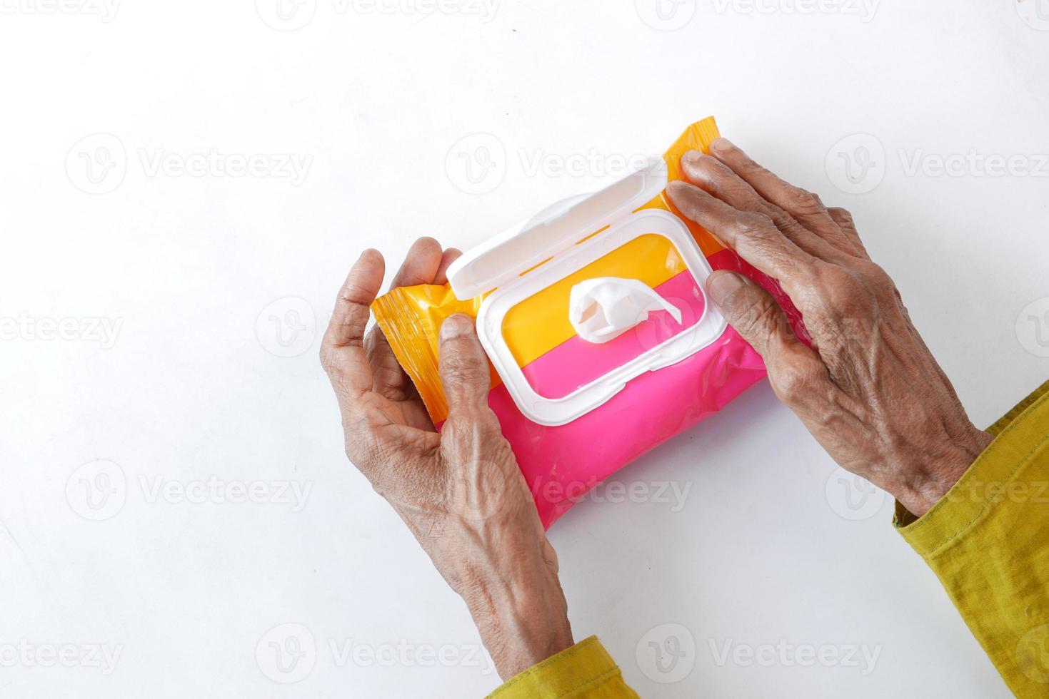 Mano de las mujeres mayores con toallitas limpiadoras húmedas sobre fondo blanco. foto