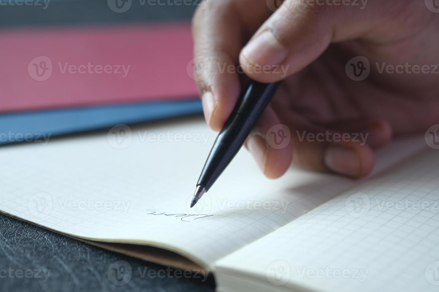 man hand writing on notepad while sited photo