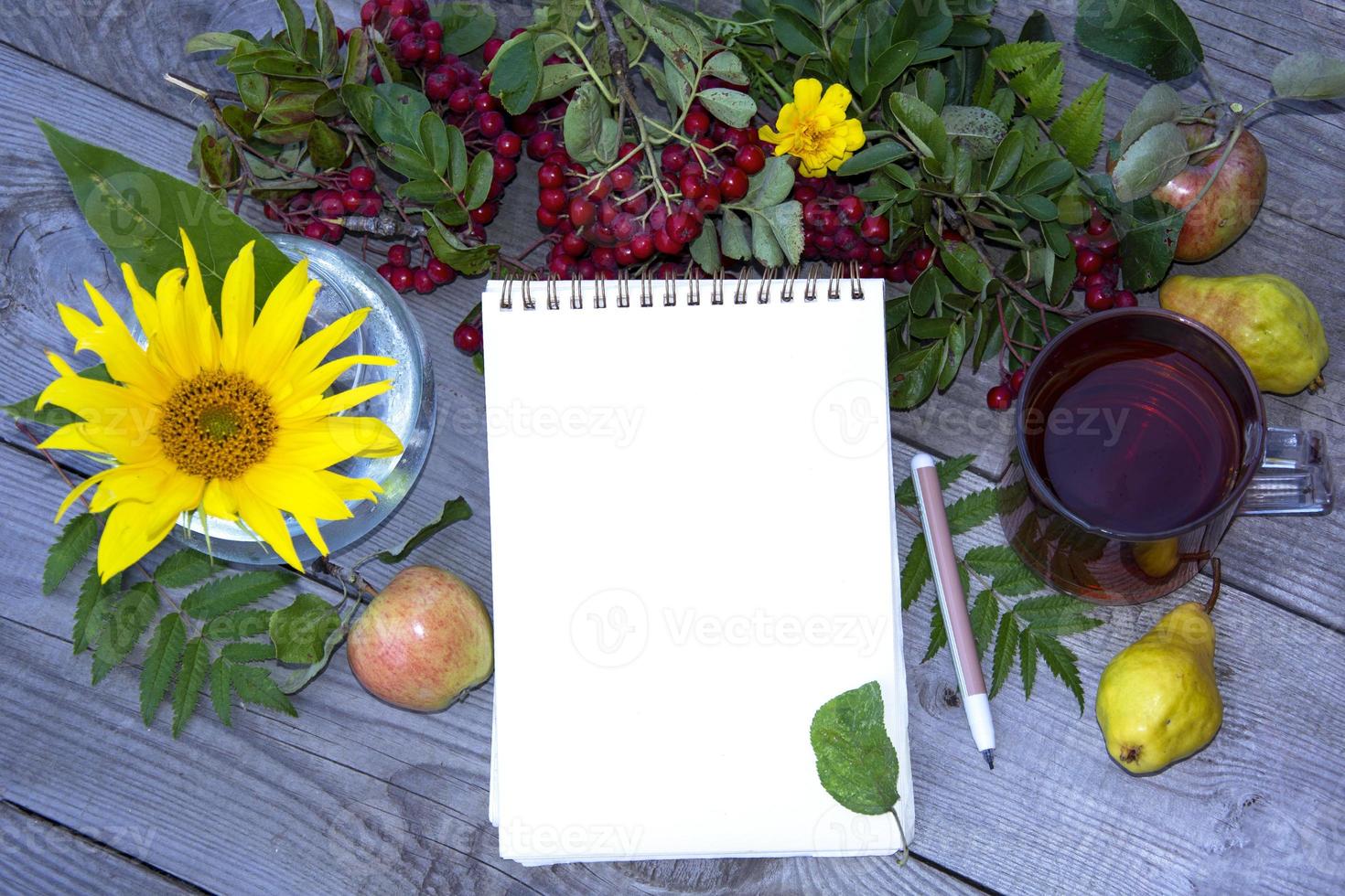 Bloc de notas con una hoja de papel en blanco para escribir. plantilla con un campo de texto. Fondo natural de bayas, flores y una bebida. foto