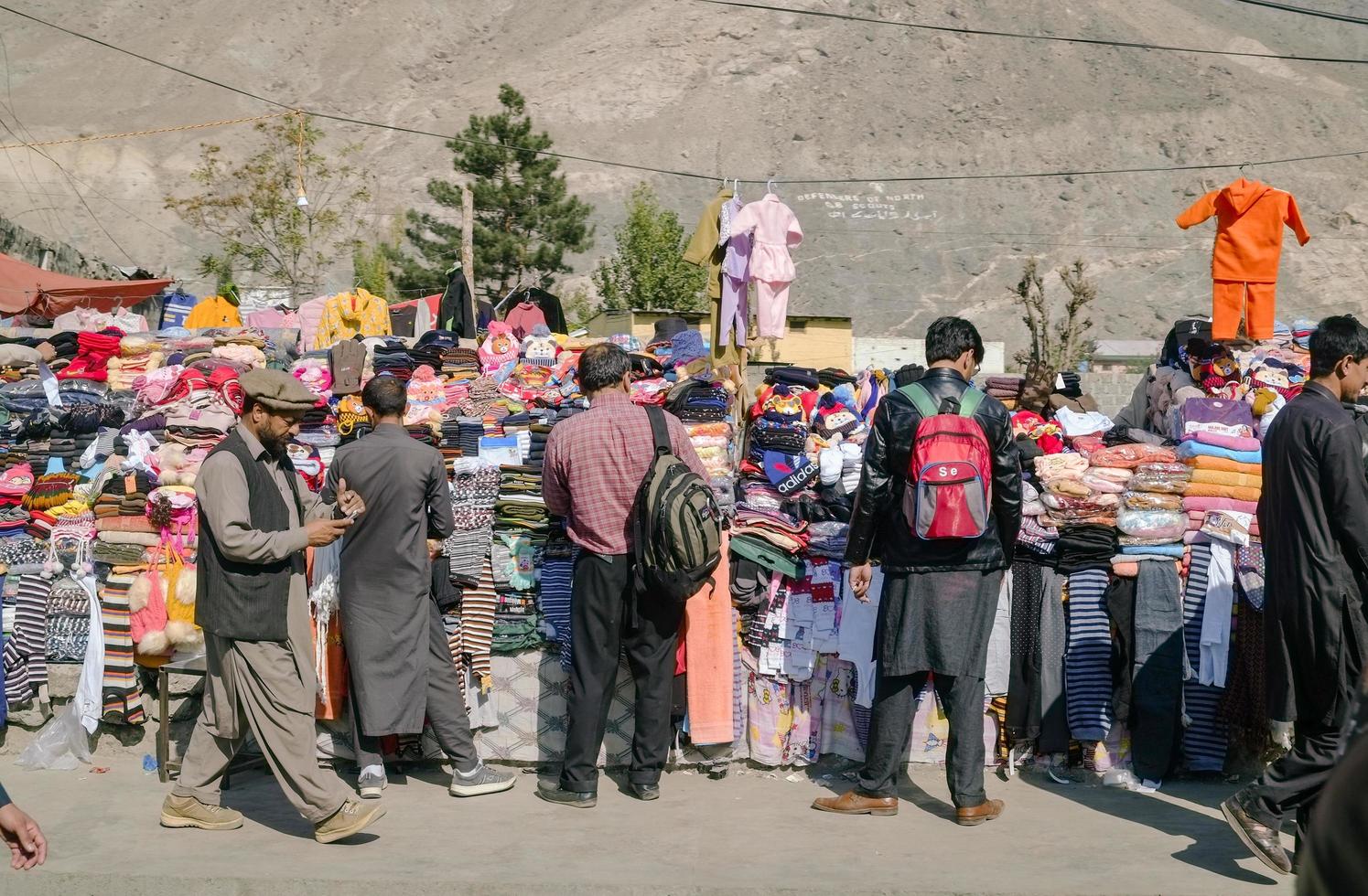 Gilgit, Pakistán, 2017 - Personas que eligen productos en un puesto de ropa local. foto