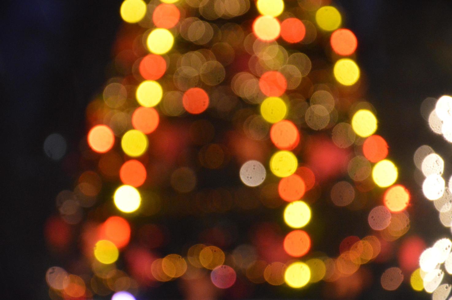 Evening and night Christmas tree glows with lights in the city in winter blurred photo