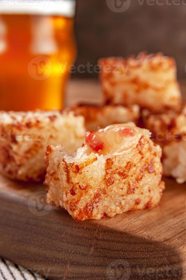 Tapioca dice with pepper jelly and glasses of beer on a wooden cutting board - Closeup. photo