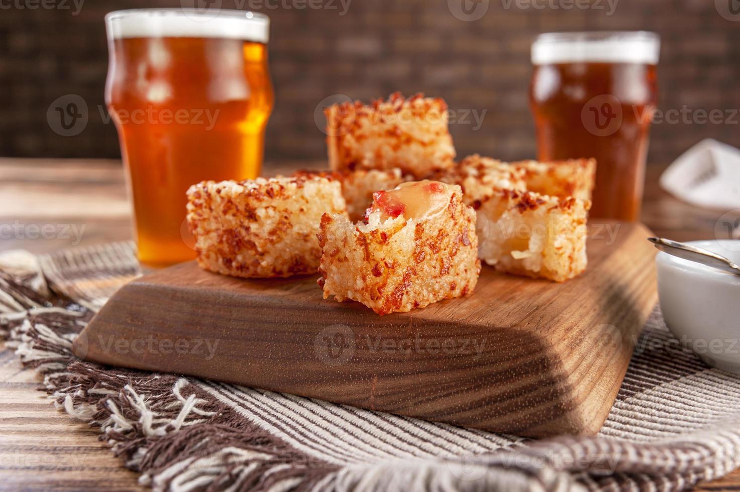 Tapioca dice with pepper jelly and glasses of beer on a wooden cutting board photo