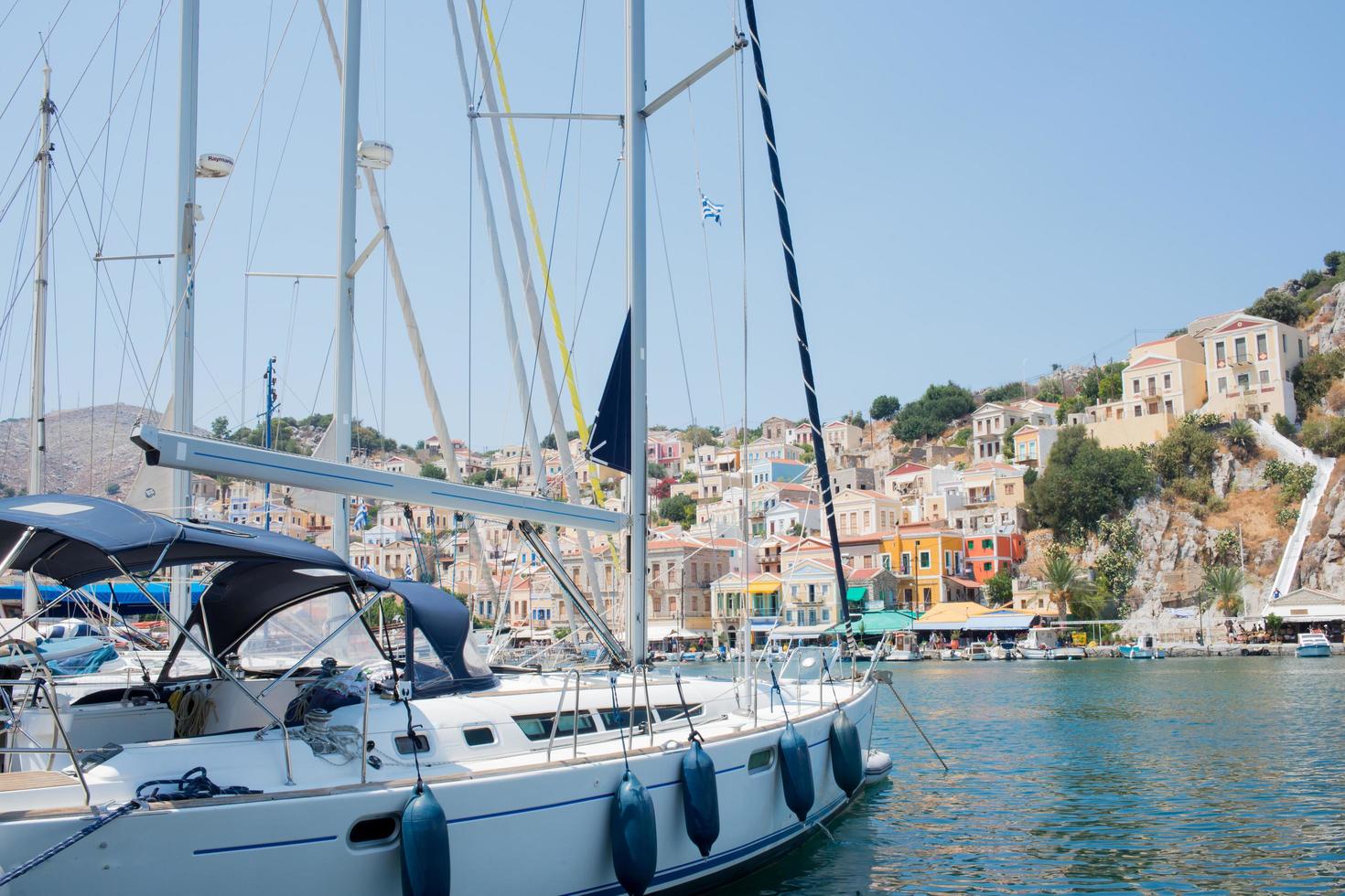 White yacht arriving to colorful Symi harbour on a sunny day. Greece. photo