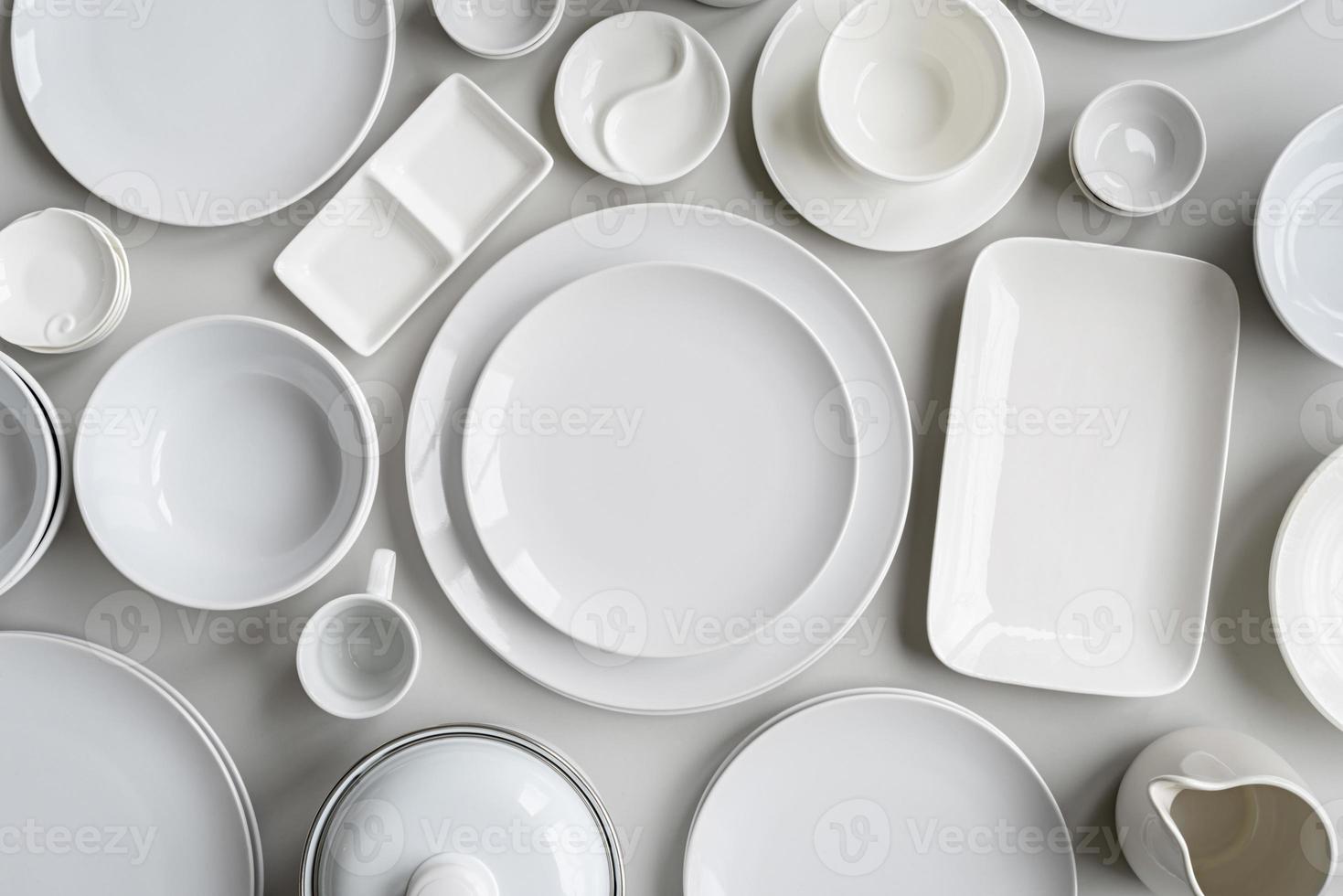 piles of white ceramic dishes and tableware top view on gray background photo