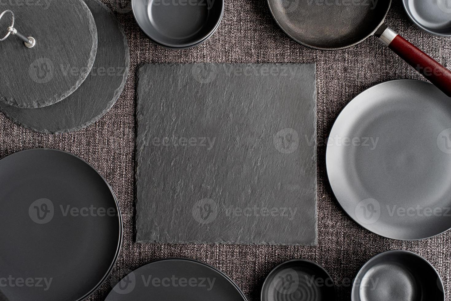 piles of black ceramic dishes and tableware top view on gray background photo