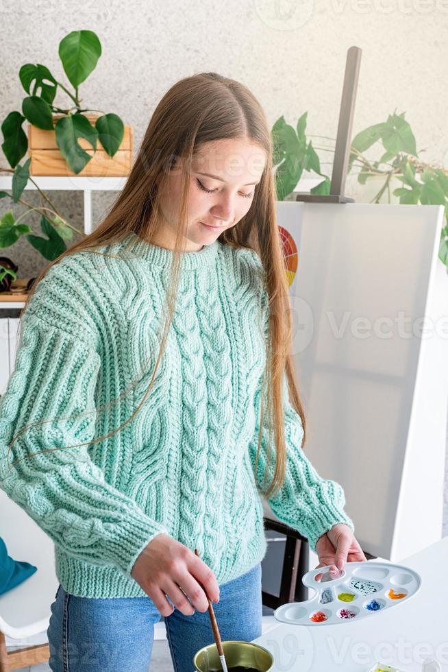 Young teenage woman artist holding color palette working in her studio photo