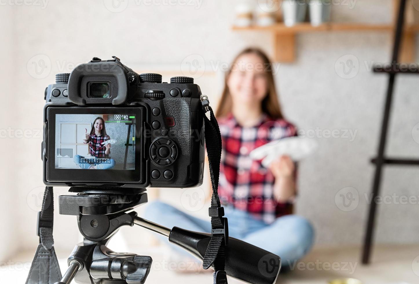 Mujer haciendo un video para su blog sobre arte usando una cámara digital montada en un trípode foto