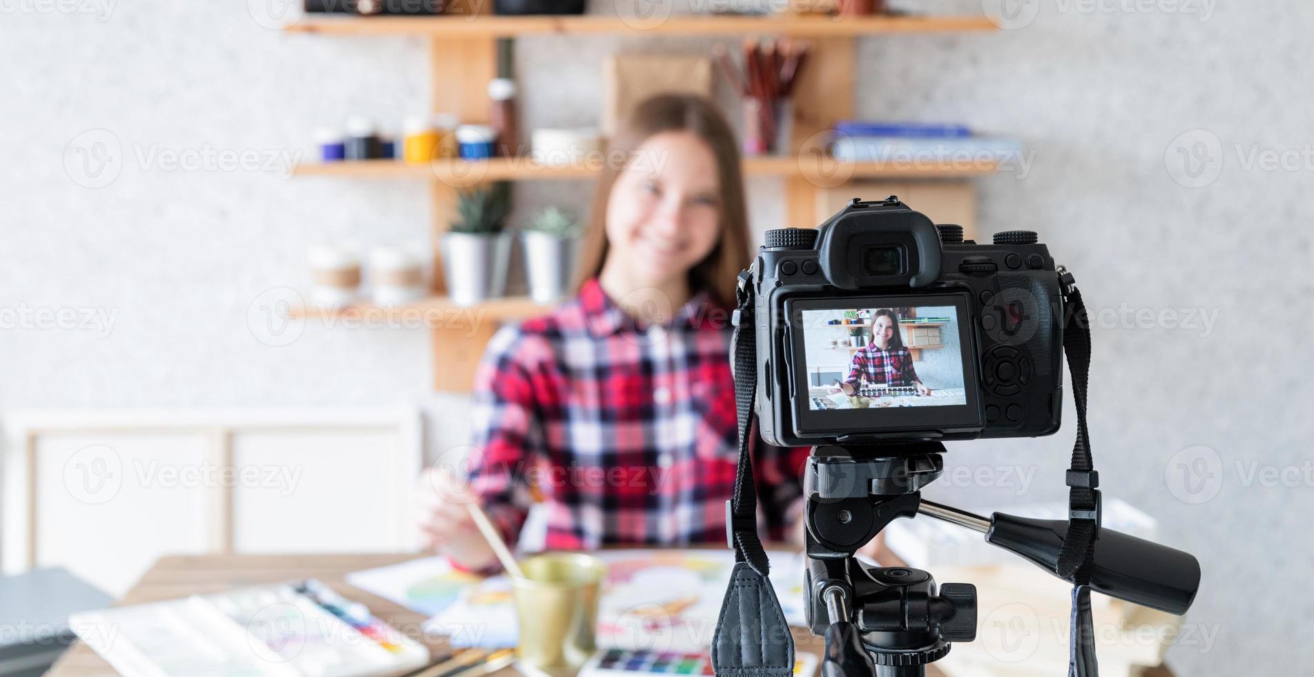 Woman making a video for her blog on art using a tripod mounted digital camera photo