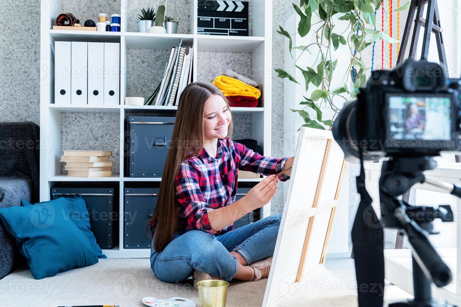 Woman making a video for her blog on art using a tripod mounted digital camera photo