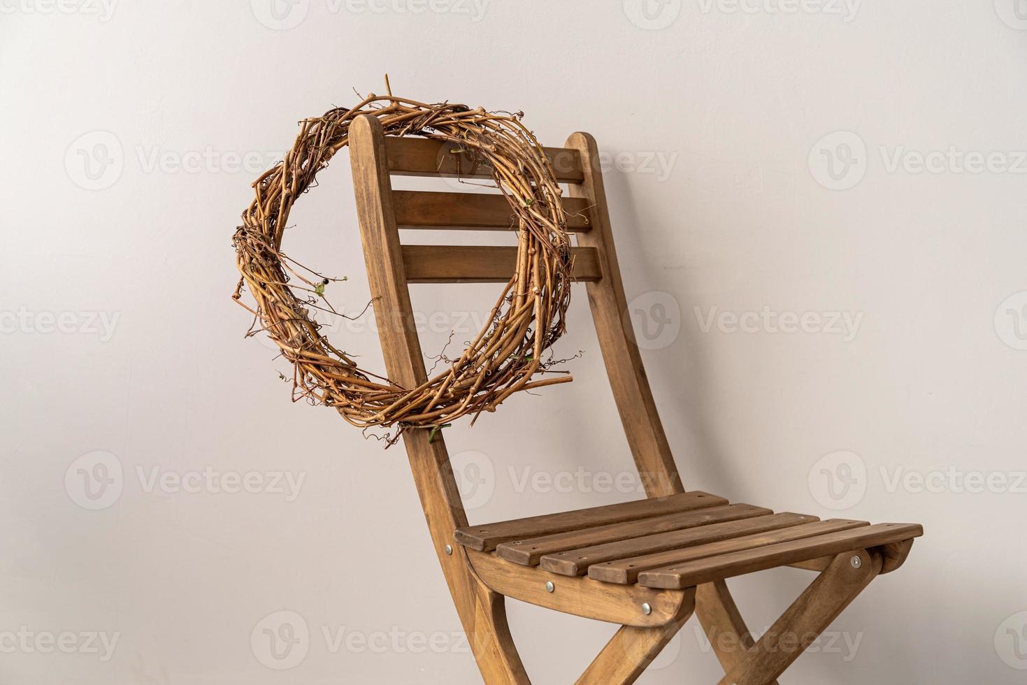 Wreath hanging on the wooden chair over grey background photo