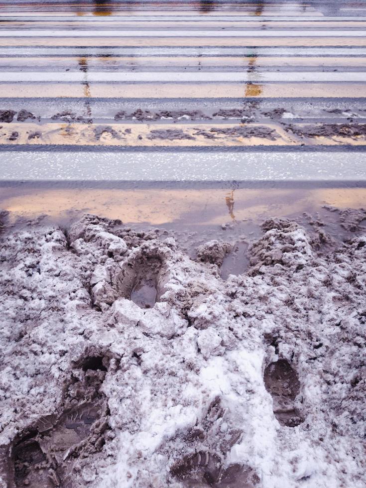 Snowy and slippery crosswalk with footprints. photo