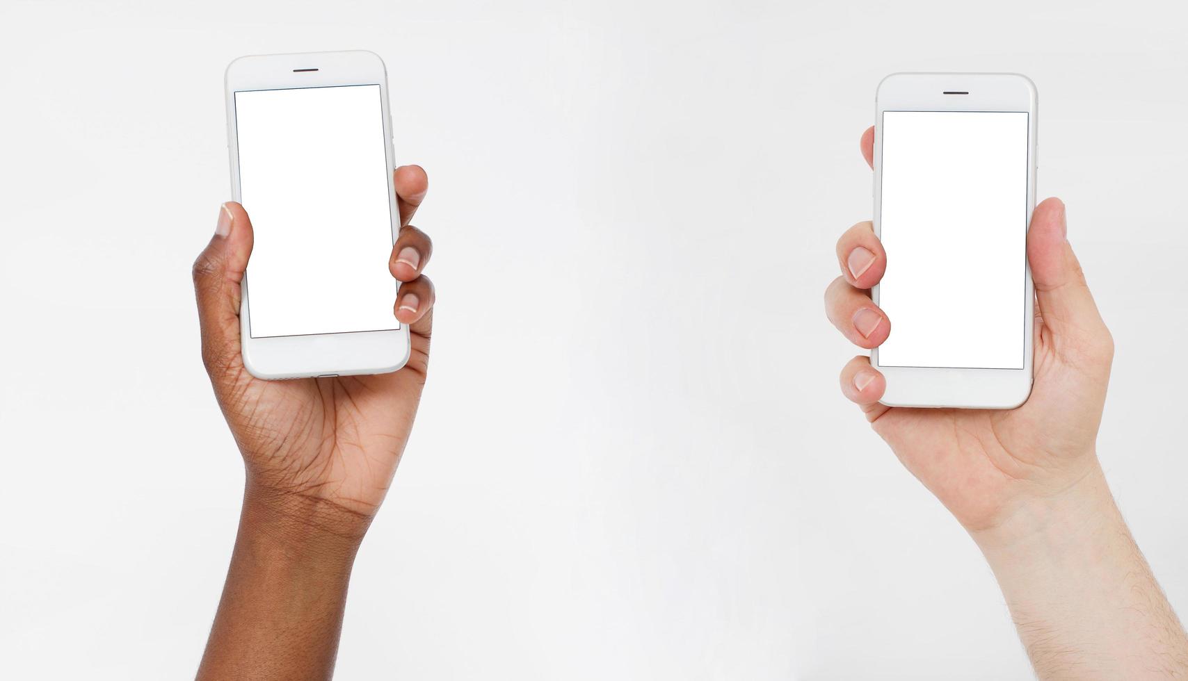 Afro american and caucasian hands hold cell phones. Blank screen smartphone. Copy space, mock up,blank,template. photo