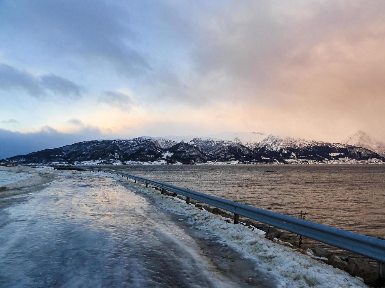 conduciendo al amanecer por el fiordo sobre hielo negro, noruega. foto