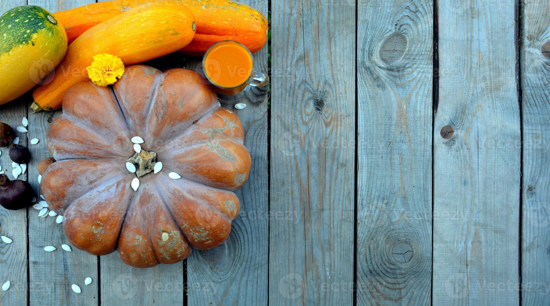 Pumpkins with zucchini on a wooden background. A glass of juice and pumpkin seeds. Natural background with pumpkins for Halloween. photo