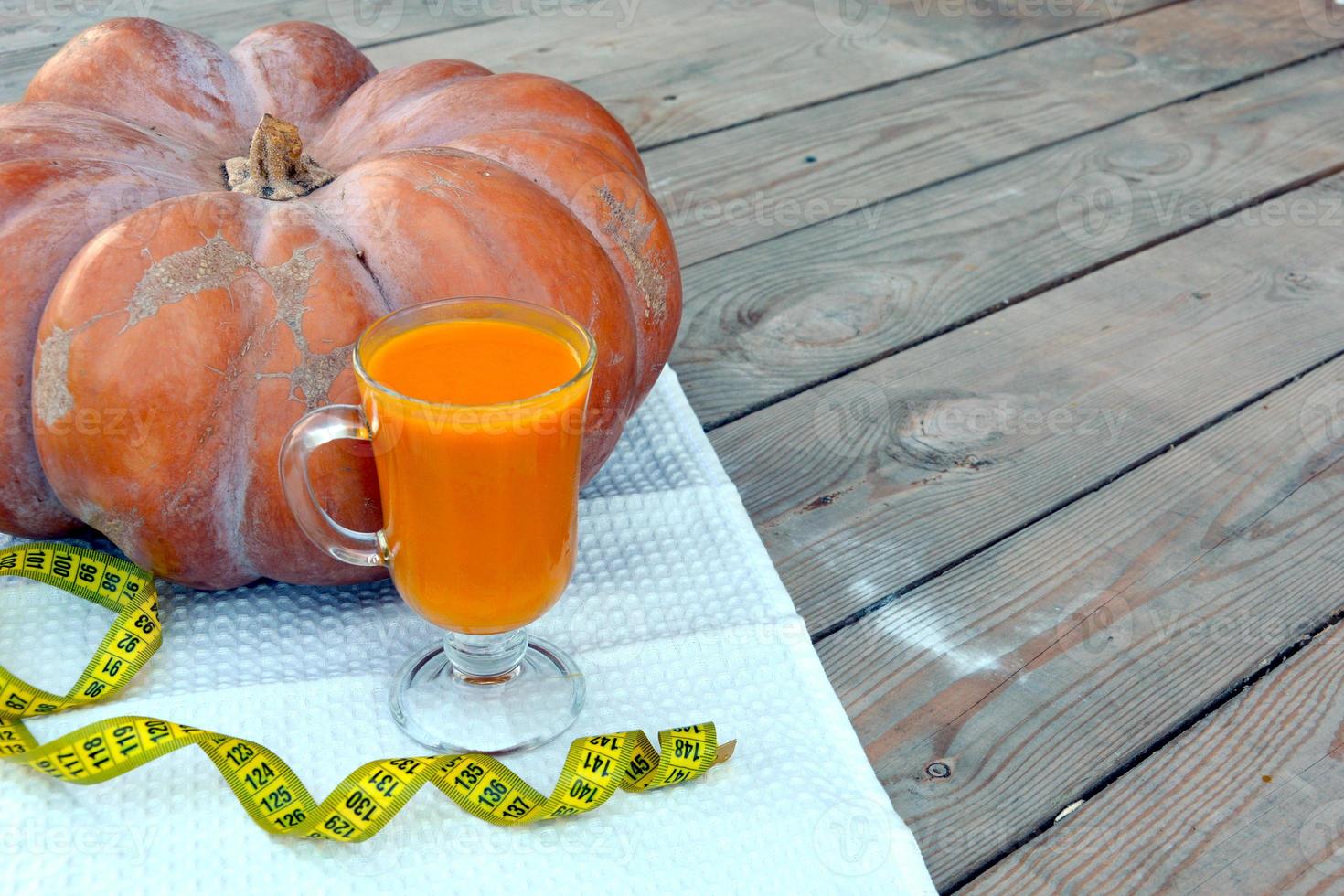 Pumpkin and pumpkin juice in a glass goblet on a white napkin. Vegetables on a wooden background. photo