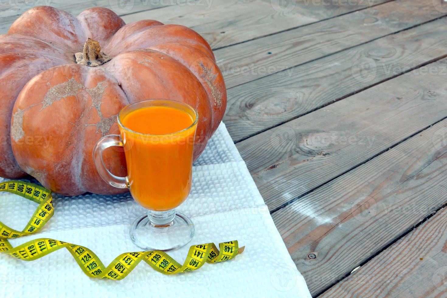 calabaza y jugo de calabaza en una copa de vidrio sobre una servilleta blanca. verduras sobre un fondo de madera. foto