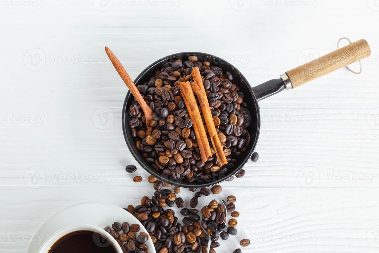 Taza de café y granos de café en la mesa de madera blanca foto