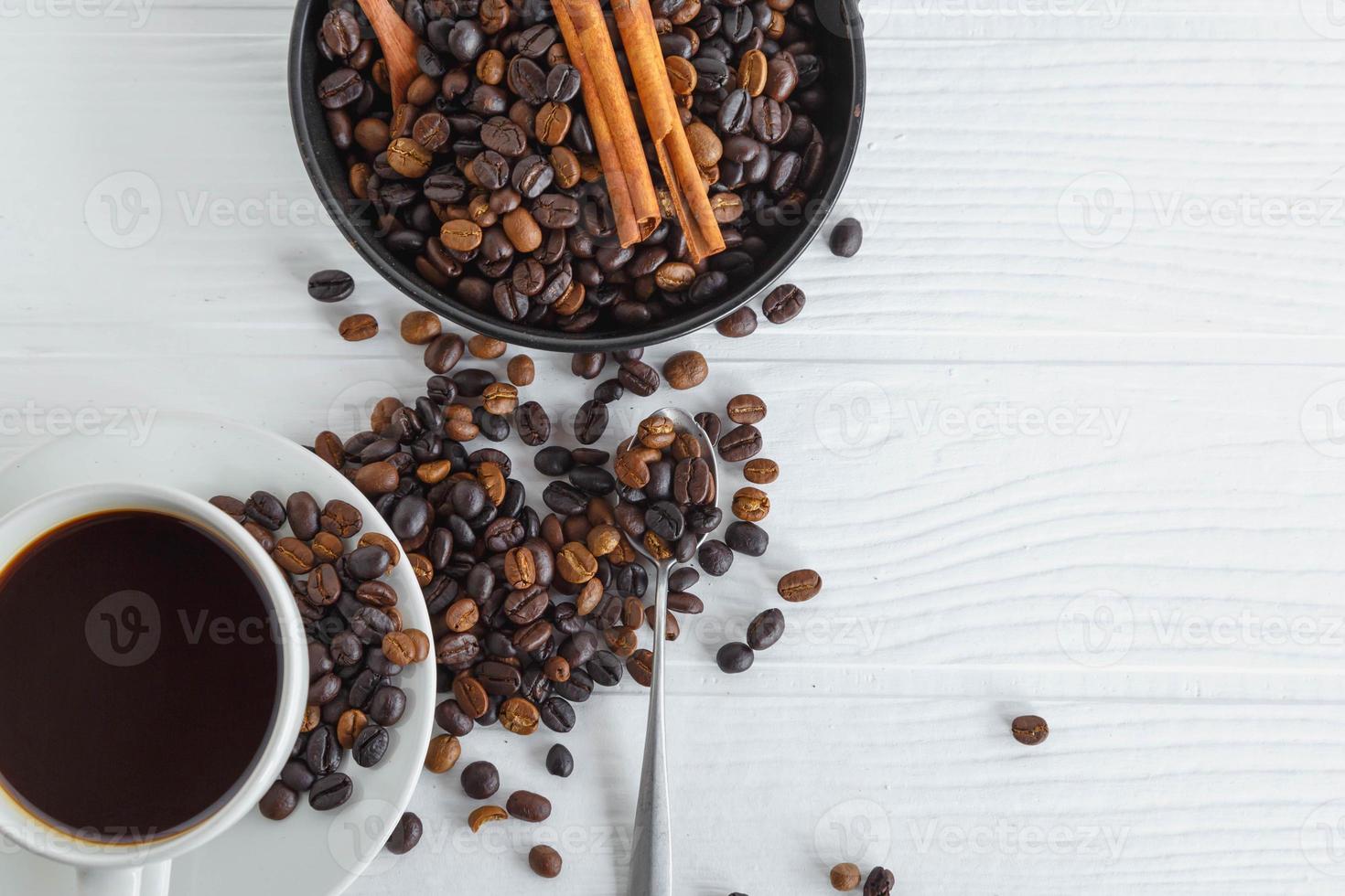 Taza de café y granos de café en la mesa de madera blanca foto