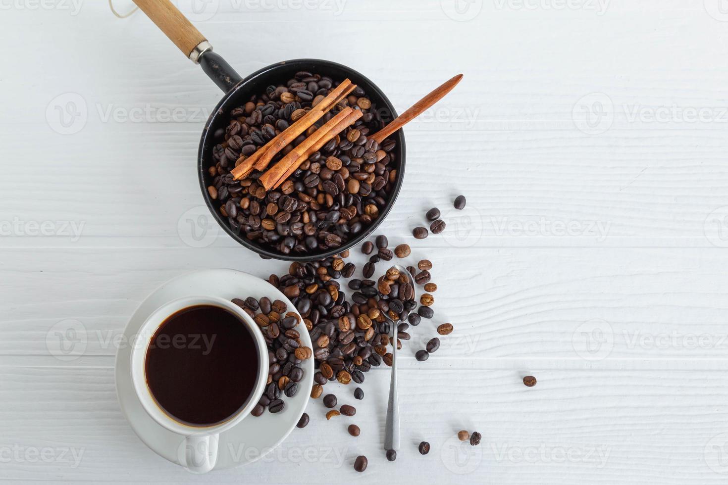 Taza de café y granos de café en la mesa de madera blanca foto